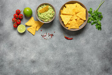 Fototapeta na wymiar Guacamole with nachos on a gray rustic background. Mexican traditional snack. Top view, flat lay, copy space.