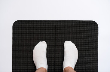Male legs in white socks standing on black yoga mat. First person view, copy space.