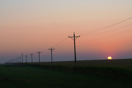 A powerline stretches to the horizon at sunset