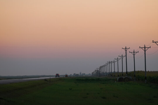 Distant cars on a flat highway at sunset