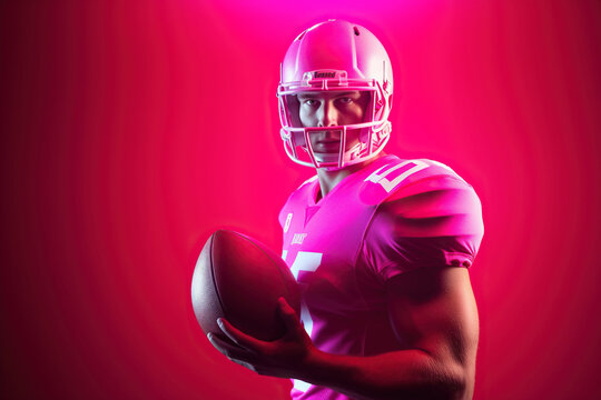 Caucasian male american football player holding ball with neon pink lighting - Powered by Adobe