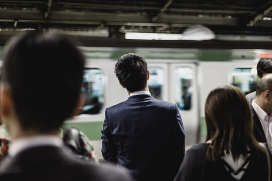 Passengers traveling by Tokyo metro. Business people commuting to work by public transport in rush hour. Shallow depth of field photo.