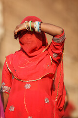 JODHPUR, RAJASTHAN, INDIA: young woman elegantly hides her face behind the transparent scarf of her red sari