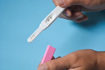 Close up of a tool for checking pregnancy that is being opened and marked with 2 lines