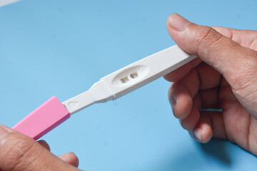 Close up of a tool for checking pregnancy that is being opened and marked with 2 lines