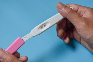 Close up of a tool for checking pregnancy that is being opened and marked with 2 lines