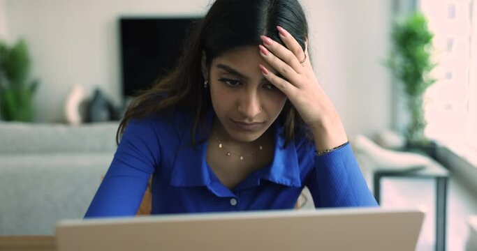 Close up frustrated young Indian woman work on laptop, looks desperate, shocked read bad on-line news, feel stressed by important data loss, feeling tired, overloaded, having troubles at hard workday