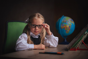Portrait of a little blonde schoolgirl girl with glasses 