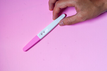 Close up of a tool for checking pregnancy that is being opened and marked with 2 lines