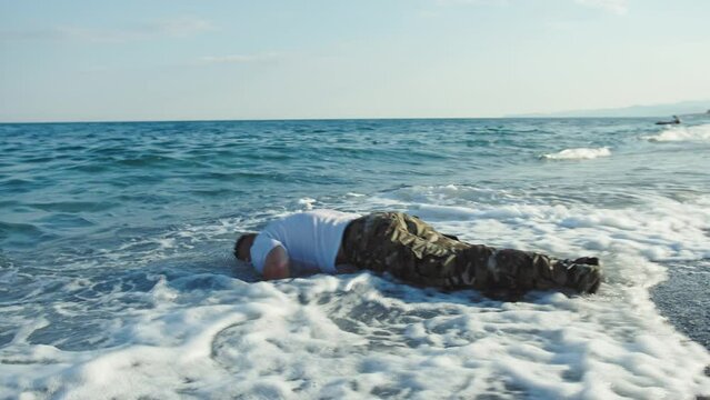 Soldier does push ups in the sea waves