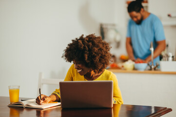 A focused african american woman is using a laptop for an online webinar