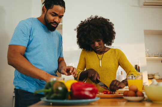 An african american couple is preparing lunch together at home in the kitchen.