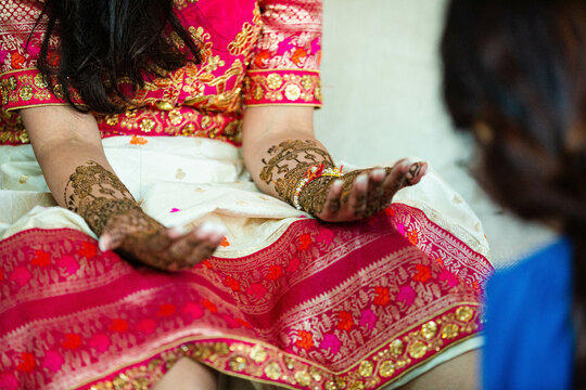 Closeup of henna tattoos being applied to a person in traditional Indian attire at a wedding.