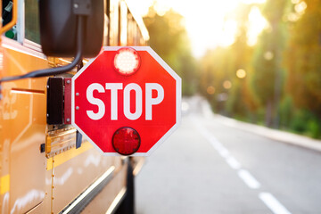 Yellow school bus with red stop sign standing on the road - Powered by Adobe