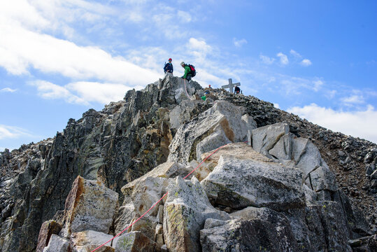Alpinist couple standing on the rocks at the Muhammad Pass of Aneto Peak, Spain. Enjoying a beautiful mountain day.