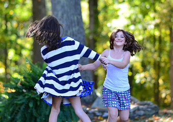 Children holding hands running in circles, girls playing ring around the roses, during fall.