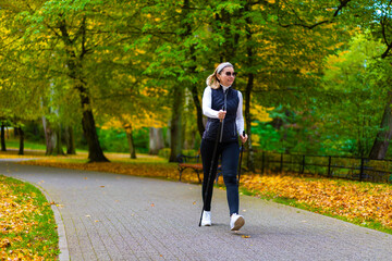 Fototapeta premium Nordic walking - woman exercising in city park 