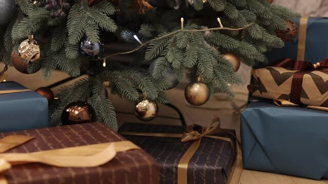 Christmastime celebration, Christmas, New Year gift. Gft boxes are tied up with ribbons and decorated with Christmas ornaments. Background is of fir tree in the room and beautiful Christmas gift boxes