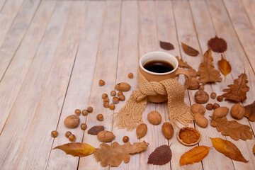 Autumn, autumn leaves, a hot cup of coffee and a warm scarf on the background of a wooden table. Seasonal, morning coffee, Sunday relaxation and still life concept.

