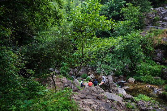 A group of people have a snack in the forest around the Belelle waterfall in Neda, Galicia