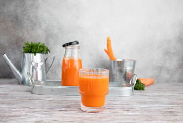 Carrot juice in a glass , carrot,carrot juice in a glass bottle, carrots in a jar in the background, fresh carrots