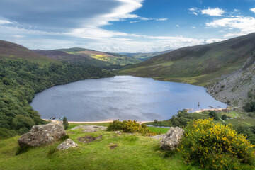 Fototapeta na wymiar View on Lough Tay, called Guiness Lake with moored Viking longships and wooden village in Wicklow Mountains, Ireland