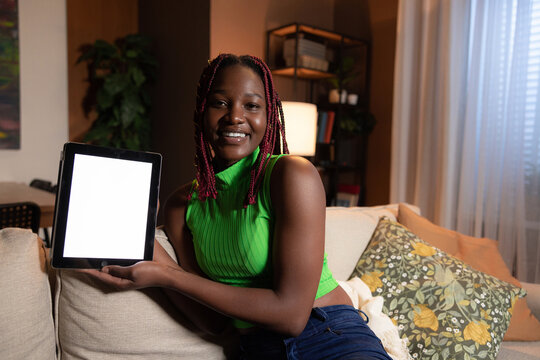 Beautiful cheerful attractive young African American dark skinnedfitness enthusiast using tablet accessing workout routines and track her progress on fitness apps mockup white screen tablet concept