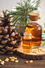 Organic essential oil, pine nuts, cedar cone on rustic wooden dark background. Concept of natural ingredients, naturopathy, herbal extracts and essence. Alternative medicine, aromatherapy