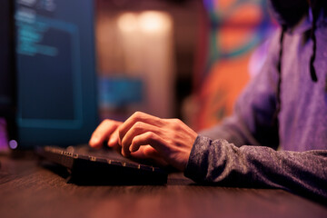 Hacker hands writing virus software code and typing on keyboard. Young internet criminal...