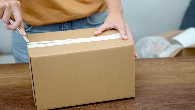 A young lady use utility knife to open package mock up , unboxing the cardboard box online shopping. 