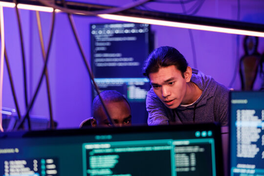 Criminals hacking into computer system while planning cyberattack and discussing phishing technique. Hackers doing ddos attack to break website and running malware code on screen