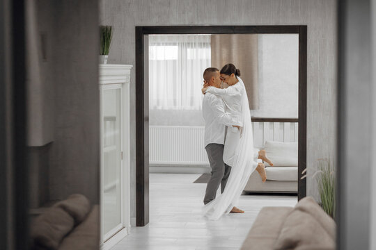 Happy bride and groom in a hotel room in the morning. Brides in love. A confident girl is a bride in the arms of the groom. Preparation for the wedding