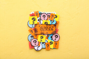 Notebook with quiz card and question marks on yellow background