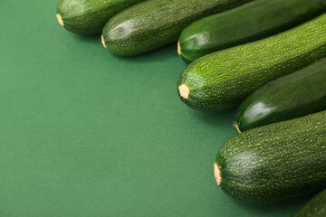 Many fresh zucchini on green background