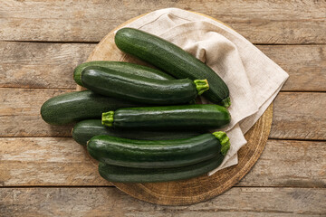 Wicker mat with many fresh zucchini on brown wooden background