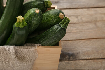 Box with many fresh zucchini on brown wooden background