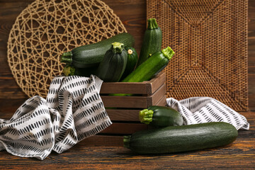 Box with many fresh zucchini on brown wooden background