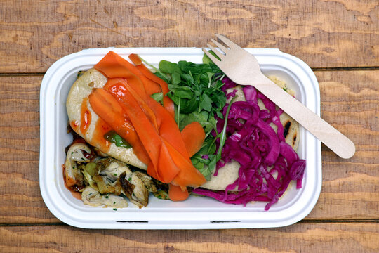 Takeaway meal of chicken with pitta bread and fresh raw vegetables.