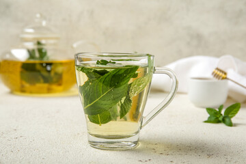 Teapot and cup of fresh mint tea on grunge light table