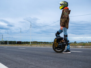 Man on a mono wheel, helmet and knee pads. Modern portable electric transport. Mono wheel with...