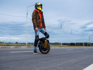 Man on a mono wheel, helmet and knee pads. Modern portable electric transport. Mono wheel with suspension © pavelkant