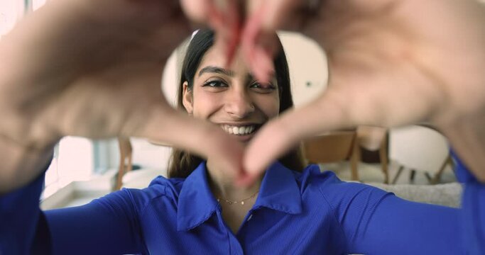 Close up portrait happy Indian woman in love showing heart symbol to camera, express sincere feelings, demonstrate gratitude, express positive feedback for services, health insurance. Donation sign