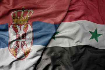 big waving national colorful flag of serbia and national flag of syria .