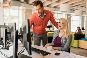 Young Caucasian coworkers using the computer together in a marketing company office