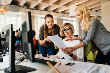 Young and diverse group of female colleagues working on a project together in a marketing company office
