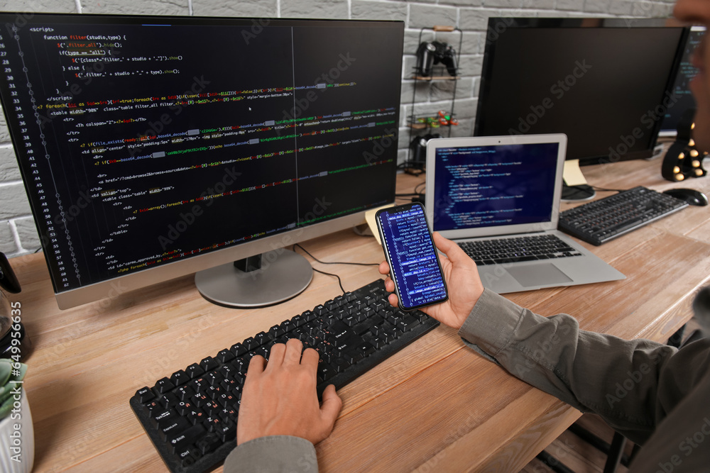 Aufkleber male programmer working with mobile phone and computer at table in office, closeup