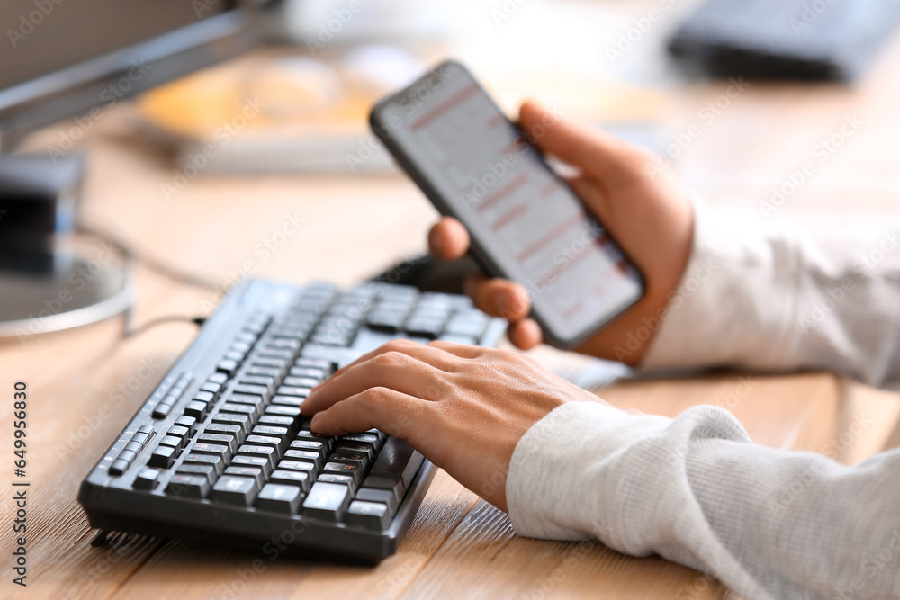 Aufkleber male programmer working with computer and mobile phone at table in office, closeup