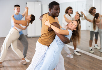 Cheerful diverse young adult people dancing together active expressive dances in pairs in modern class
