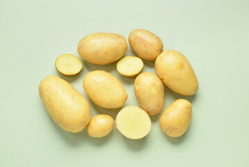 Raw potatoes on green background