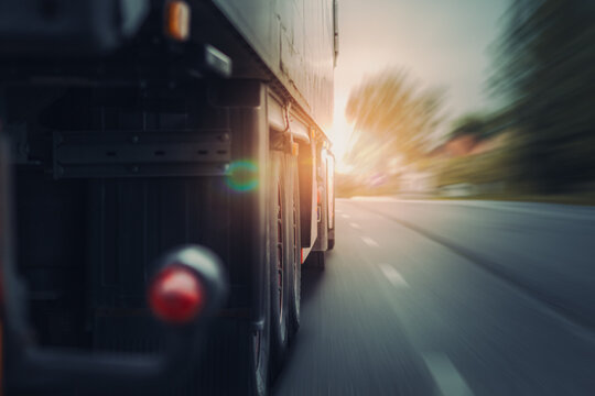 lkw von hinten f&auml;hrt schnell auf stra&szlig;e mit aspahlt bei sch&ouml;nen sonnenstrahlen von vorne